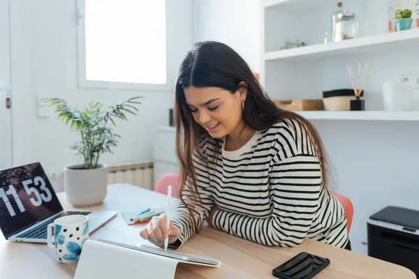 仕事や勉強で忙しい若い陽気な女性がタブレットを使用しています — ストック写真