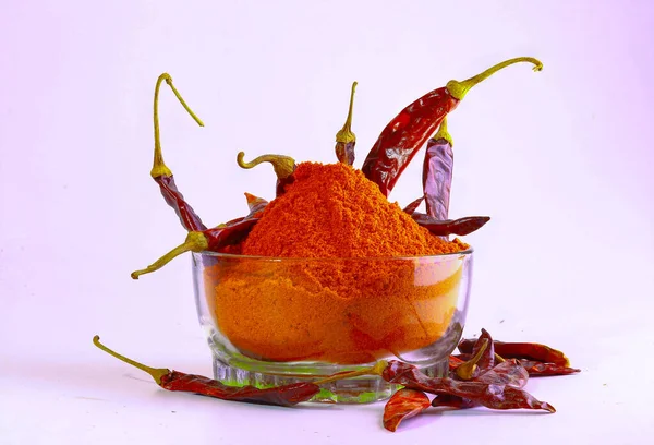 Dry red chilly peppers and a bowl of dried chilies powder isolated in the light background