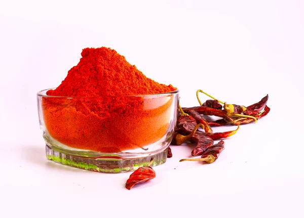 Dry red chilly peppers and powder of dried chilies in a bowl isolated in the light background
