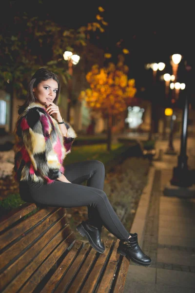 Vertical Shot Female Fashionable Jacket Posing Sitting Bench Street Night — Stock fotografie