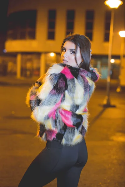 一个性感的高加索女人穿着毛茸茸的五颜六色夹克在街上摆姿势的垂直镜头 — 图库照片