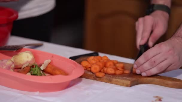 Mâle Tranchant Des Carottes Fraîches Sur Une Planche Découper Bois — Video