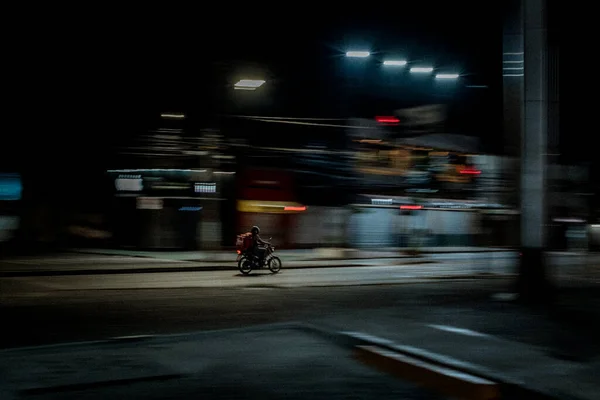 Een Koerier Een Motorfiets Een Wazige Stad Achtergrond Avond — Stockfoto