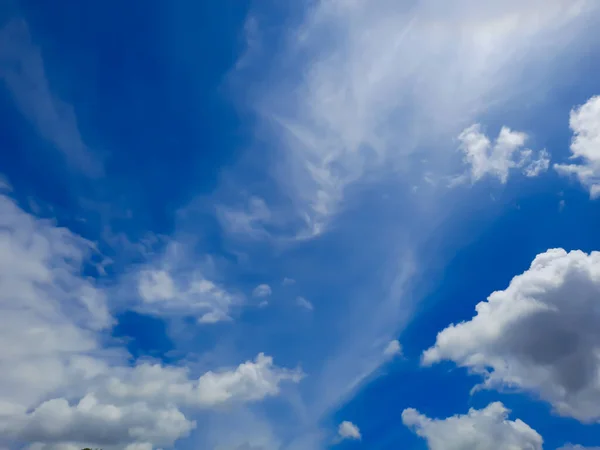 Full frame cloudscape background with white distinctive cloud shapes and blue sky against full sun.