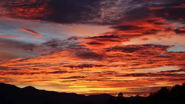 Fascynujący Widok Ognistego Zachodu Słońca Gęstymi Formacjami Chmur Nad Górami — Zdjęcie stockowe