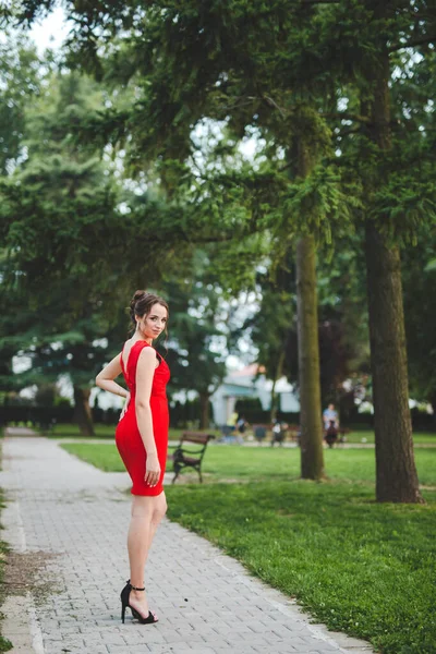 一位性感优雅的白种人女士穿着红色的衣服在公园里摆姿势 — 图库照片