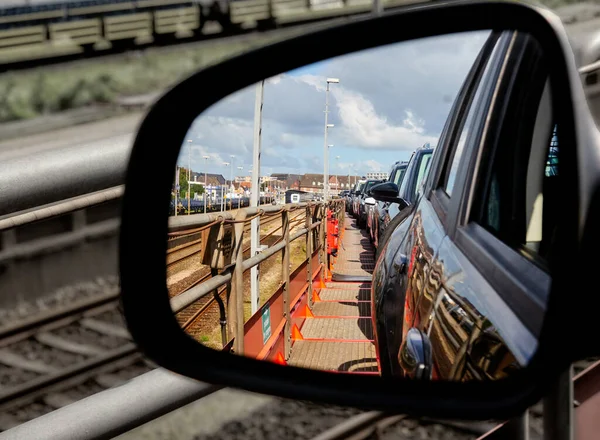 A view through the rearview mirror of cars on the upper deck of a car train