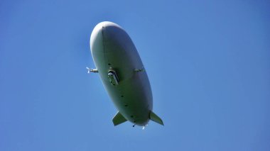A low angle view of a dirigible balloon in the blue clear sky clipart