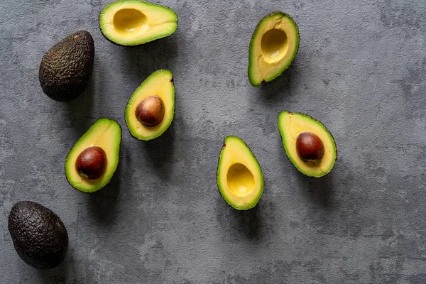 Kreativ Ovanifrån Skivad Och Hel Avokado Strukturerad Grå Bakgrund — Stockfoto