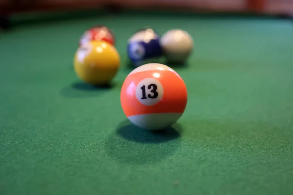 A green pool table with colored billiard balls