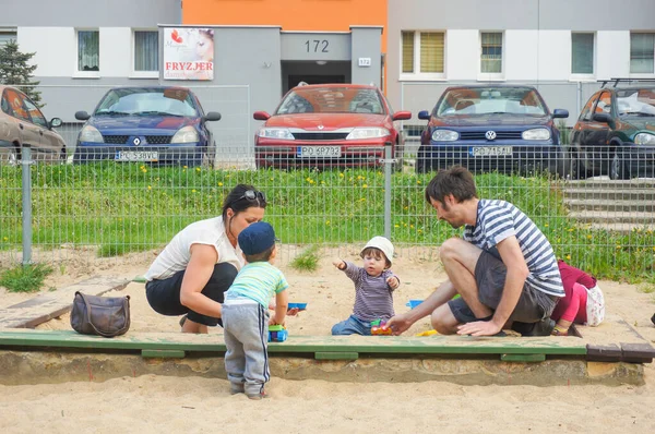 波兹南 2016年5月10日 女人和两个男孩在停车场和建筑物附近的沙坑上玩耍 — 图库照片