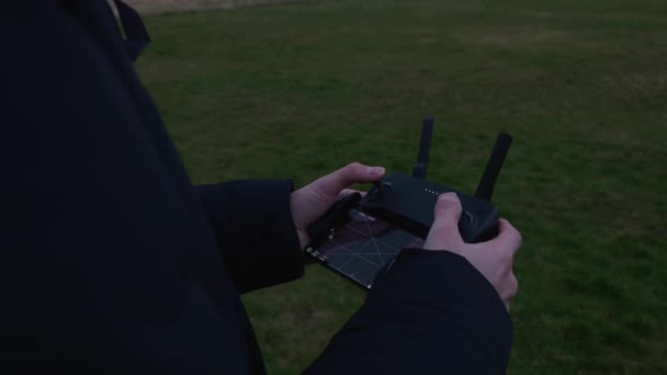 男子使用Dji控制器驾驶一架Mavic微型无人驾驶航空器在公园的草地上 — 图库视频影像