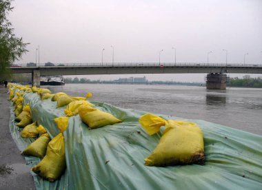 A row of large sandbags flood barricade protecting river against flooding clipart