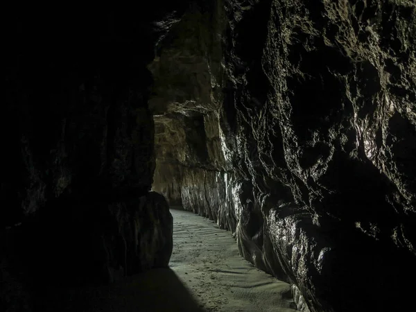A closeup shot of a dark cave from the inside with light at the end of the tunnel