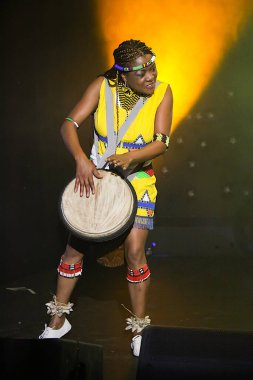 JOHANNESBURG, SOUTH AFRICA - May 03, 2019: traditional African woman in ethnical wear playing drums clipart
