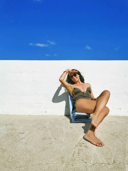 一个黑发中年西班牙裔女性日光浴和享受海滩日的垂直照片 — 图库照片