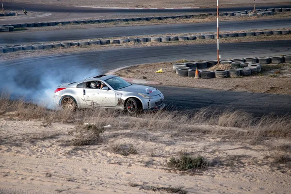 柏油路上的汽车白天在沙漠里拖着烟飞驰 — 图库照片