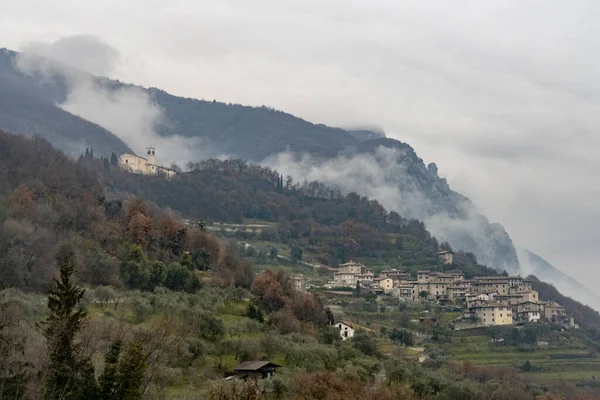 霧に囲まれた山の上の小さなイタリアの村 — ストック写真
