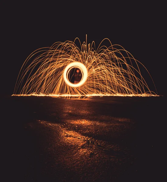 暗い場所とぬれた表面で回転し旋回する火花を生み出す男 — ストック写真