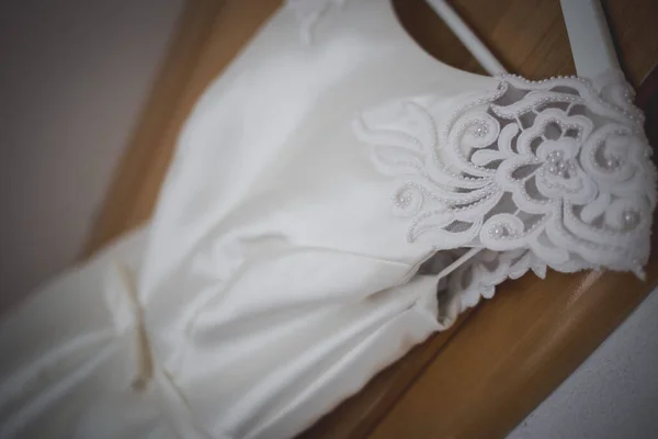 服のハンガーから吊るされた白いウェディングドレスのクローズアップ — ストック写真