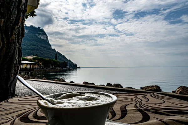 青い湖の背景に朝のコーヒーのクローズアップショット — ストック写真