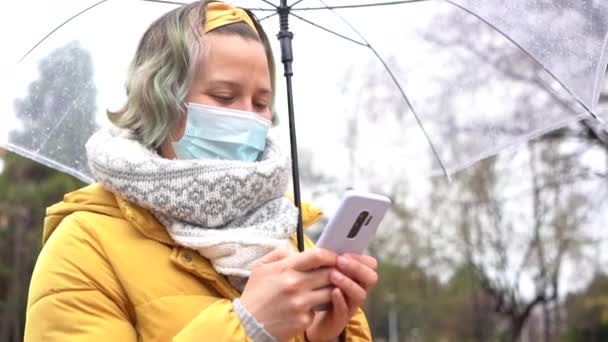 Una Joven Mujer Caucásica Con Una Máscara Sosteniendo Paraguas Caminando — Vídeo de stock