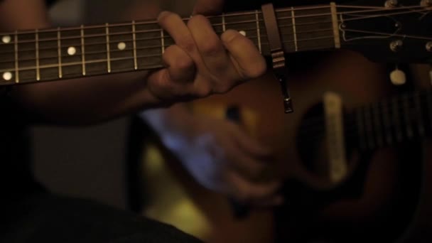 男性の手は暗い部屋でギターを弾き — ストック動画