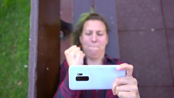 Spanyol Bir Kadının Parkta Video Oyunları Oynarken Bir Bankta Uzanması — Stok video