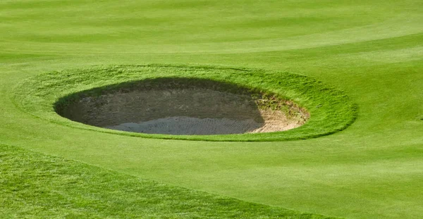 ゴルフ場の緑の芝生の上で円形のバンカーのクローズアップショット — ストック写真