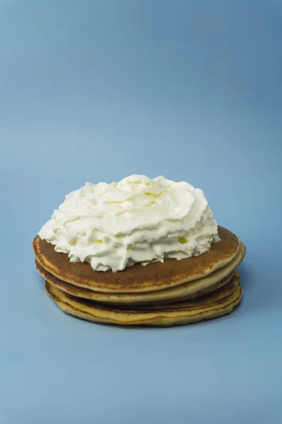 Ein Vertikaler Schuss Frischer Pfannkuchen Mit Schlagsahne Vor Blauem Hintergrund — Stockfoto