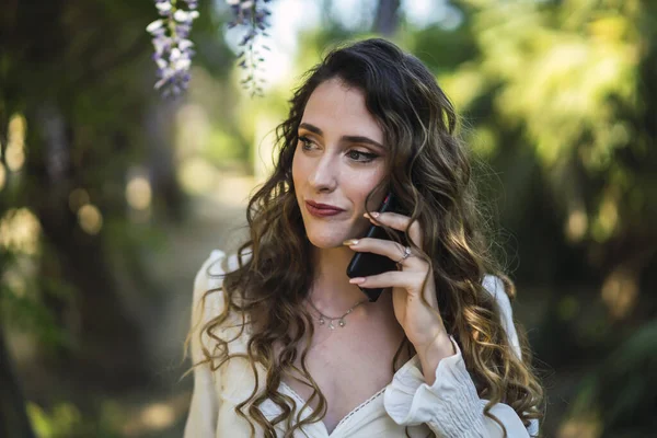 公園を歩いて彼女のスマートフォンで話している彼女の美しいスペイン語の白人女性の浅い焦点のショット — ストック写真