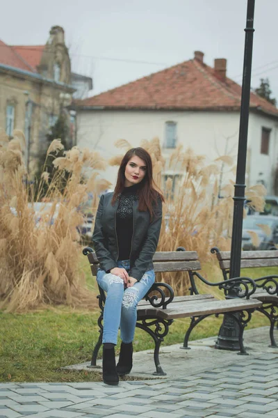 Vertical Shot Young Brunette Female Leather Coat Posing Sitting Bench — стоковое фото