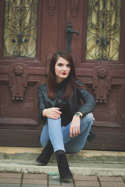 Beautiful Caucasian Female Red Lipstick Leather Coat Sitting Wooden Door — 스톡 사진