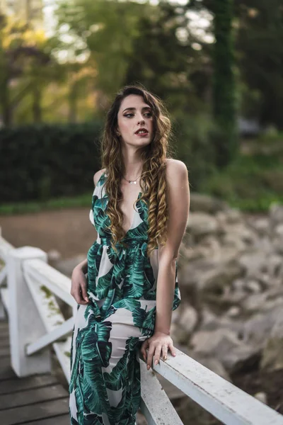 緑のドレスを着ている間 木製の橋の上に 巻き毛の美しいスペイン語白人女性の垂直ショット — ストック写真