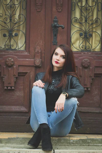 Beautiful Caucasian Female Red Lipstick Leather Coat Sitting Wooden Door — 스톡 사진