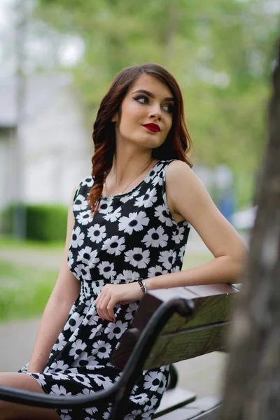 Çiçekli Elbiseli Parktaki Bankta Oturan Esmer Bir Kadının Dikey Görüntüsü — Stok fotoğraf