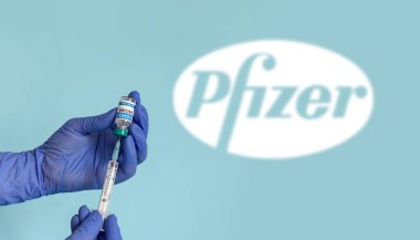 ZAGREB, CROATIA - Apr 11, 2021: Medical worker holding syringe and vaccine vial. Close-up selective focus image of nurse holding covid vaccine with pfizer logo in background. clipart