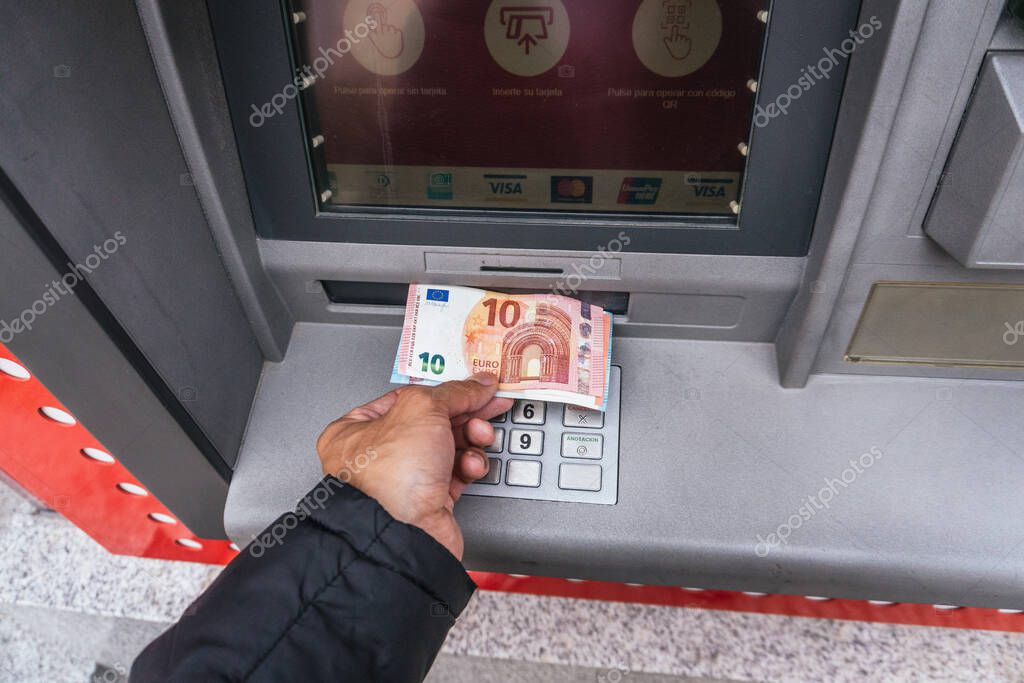 MADRID, SPAIN - Apr 14, 2021: Man's hand takes out cash euros from Santander Bank in Madrid, Spain