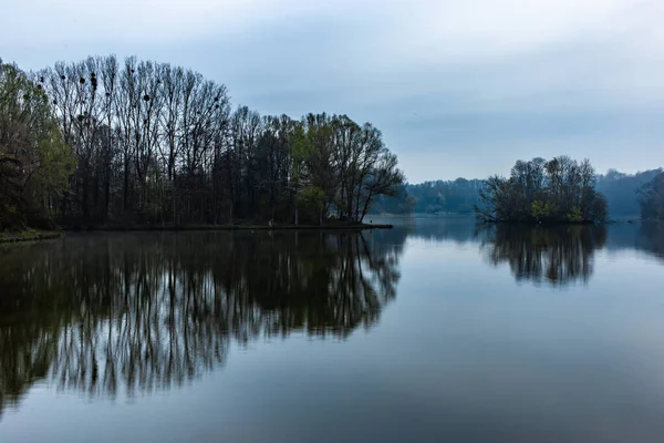 Lago Calmo Que Reflete Árvores Sob Céu Nublado — Fotografia de Stock