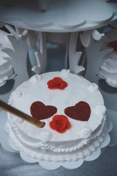 一个白色蛋糕的垂直镜头 桌子上有红心 — 图库照片