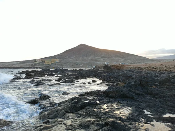 美丽的岩石海滩和周围的风景映衬着明亮的蓝天 — 图库照片