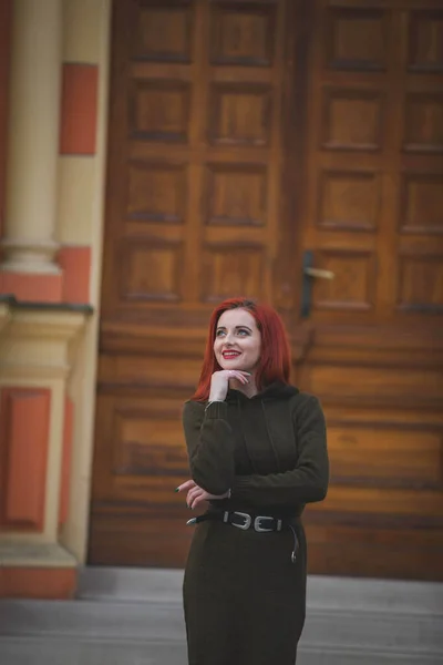 在一座具有历史意义的建筑前 一个身穿漂亮冬装的红头发年轻女性的竖直照片出现在一座历史性建筑前 — 图库照片
