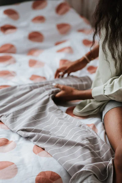 Een Jonge Afrikaanse Vrouw Vouwt Haar Grijze Witte Gestreepte Shirt — Stockfoto