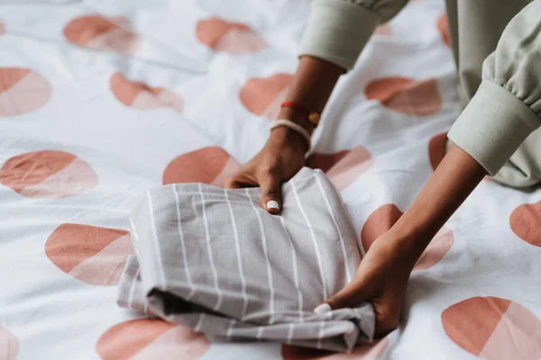 Een Jonge Afrikaanse Vrouw Vouwt Haar Grijze Witte Gestreepte Shirt — Stockfoto