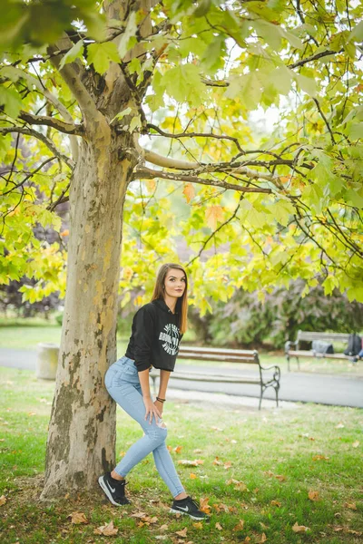 Uma Jovem Morena Caucasiana Posando Perto Uma Árvore Com Folhas — Fotografia de Stock