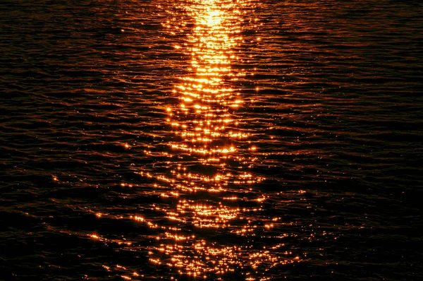 Eine Silhouettenaufnahme Des Ruhigen Wassers Während Eines Orangen Sonnenuntergangs — Stockfoto