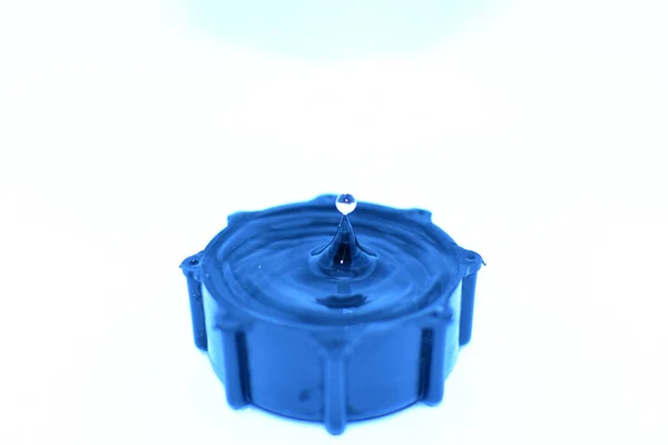 白い背景に隔離された小さな青い容器に落下する水の塊 — ストック写真