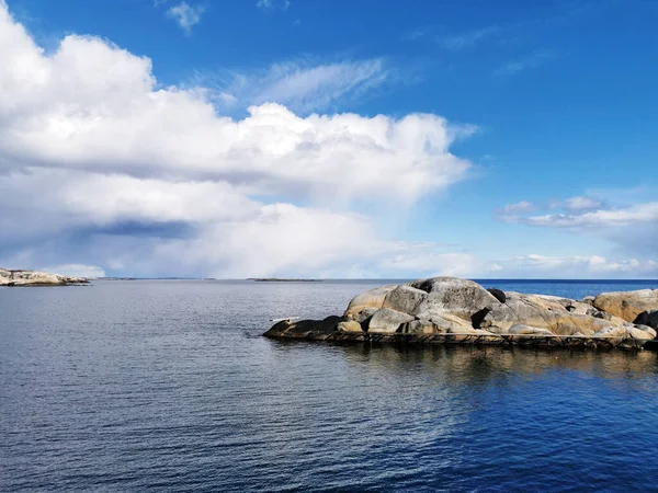 ノルウェーのラニフカの明るい曇り空の下で反射する水の体に大きな岩の山の豪華なショット — ストック写真