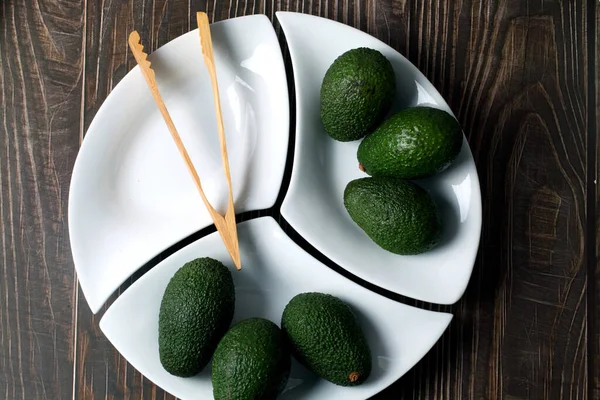 Colpo Verticale Avocado Verde Hass Piatto Bianco Forma Dispari Pinze — Foto Stock