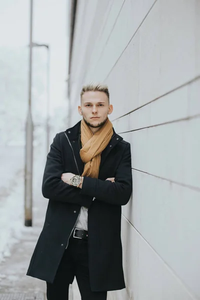 Handsome Man Black Winter Outfit Brown Scarf Leaning Wall Hands — стоковое фото